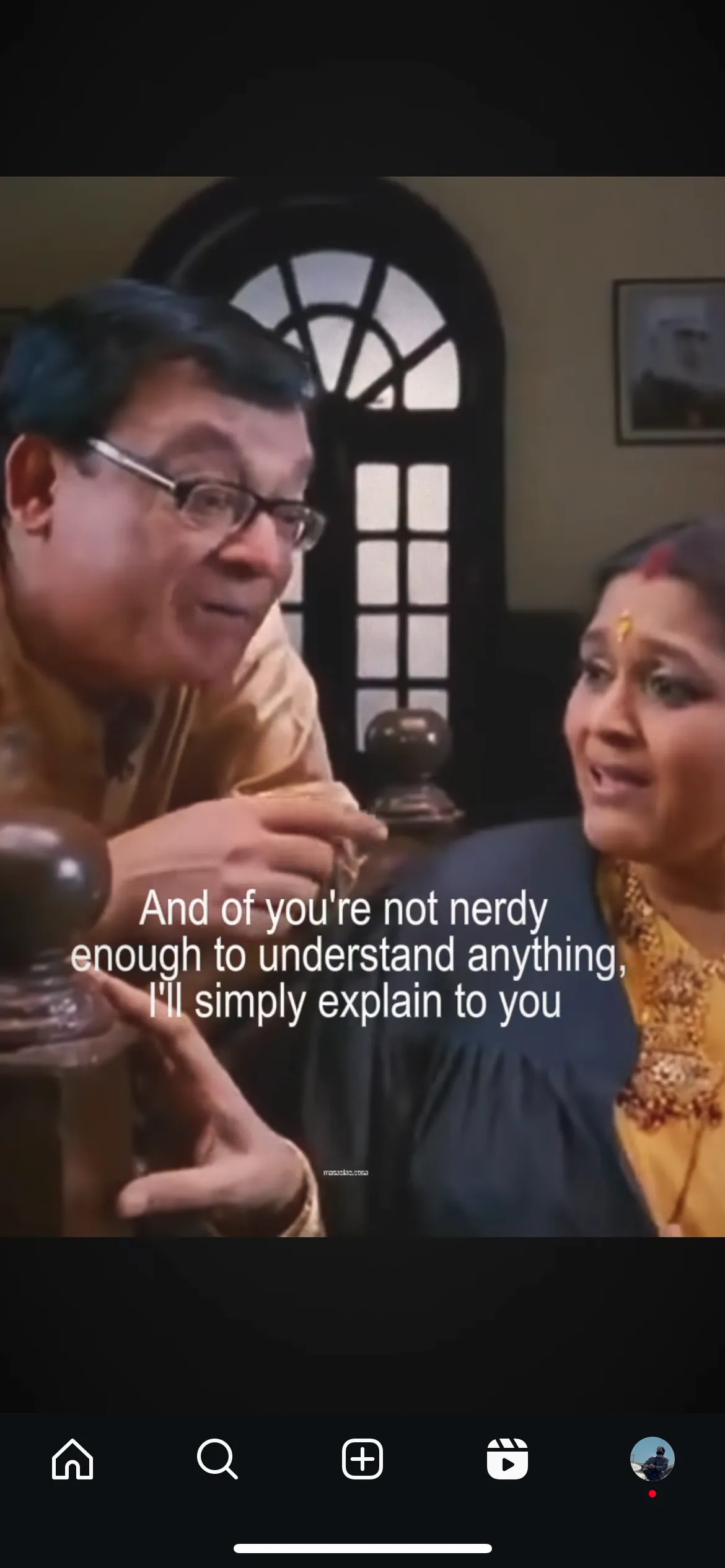 Screenshot of a subtitled Hindi TV scene: a man in glasses tells a woman, And of you’re not nerdy enough to understand anything, I’ll simply explain to you